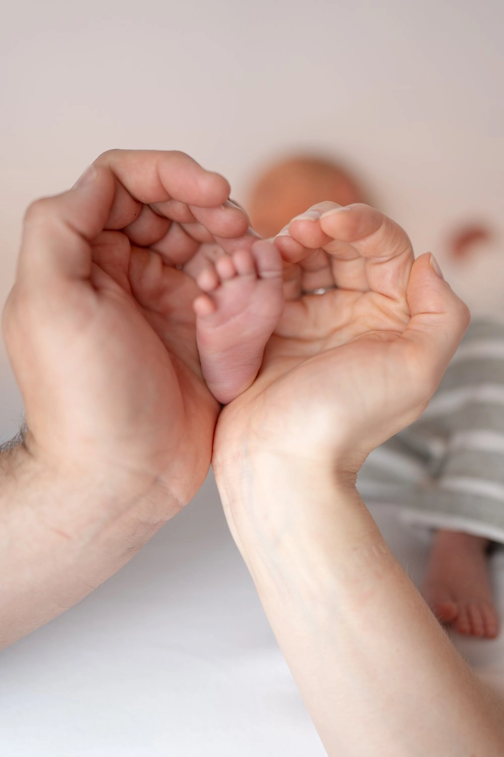 Erwachsene Hände halten die kleinen Füße eines Babys behutsam zusammen.