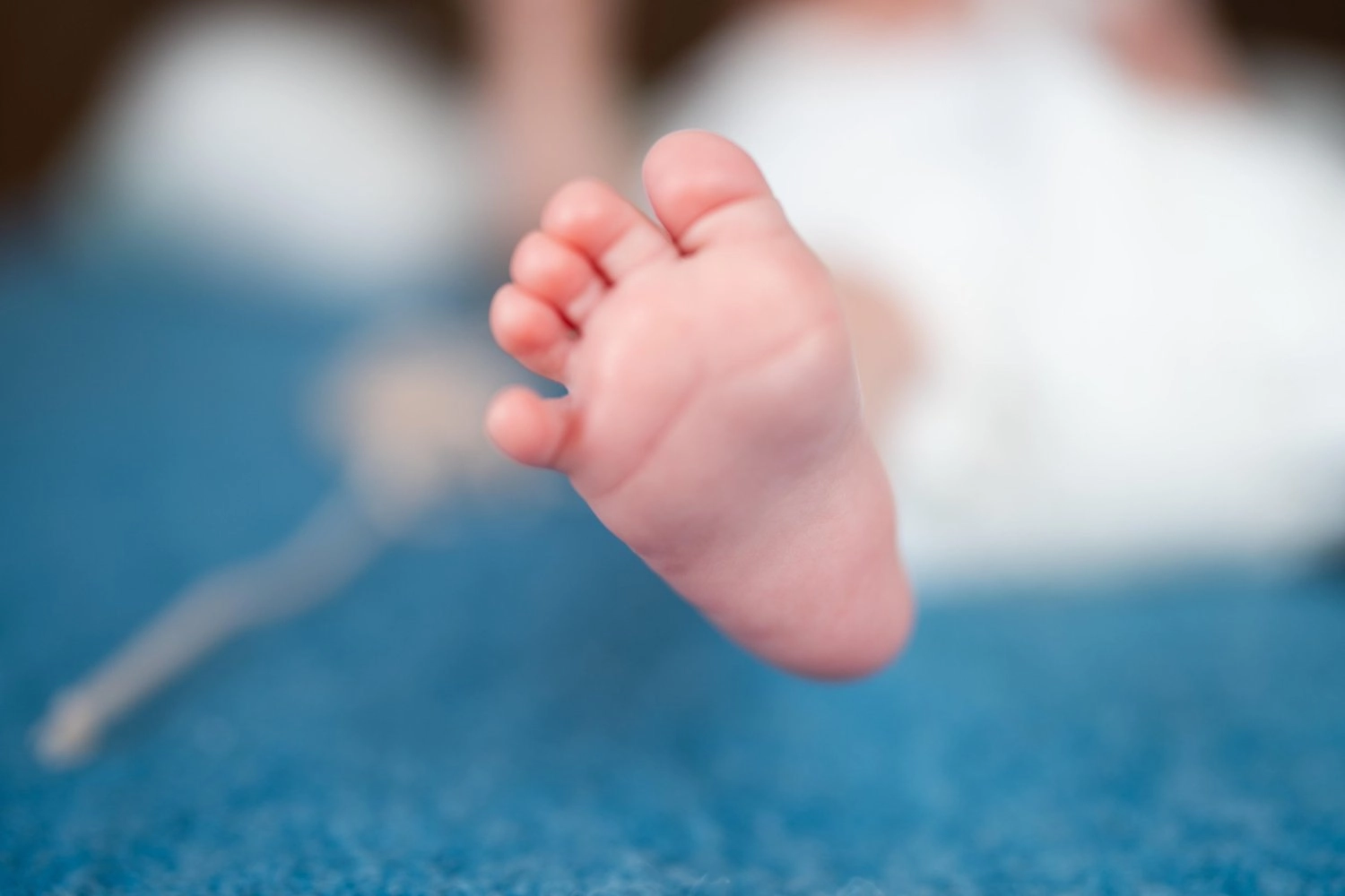 Ein kleiner Babyfuß ist vor einem weichen blauen Hintergrund zu sehen.
