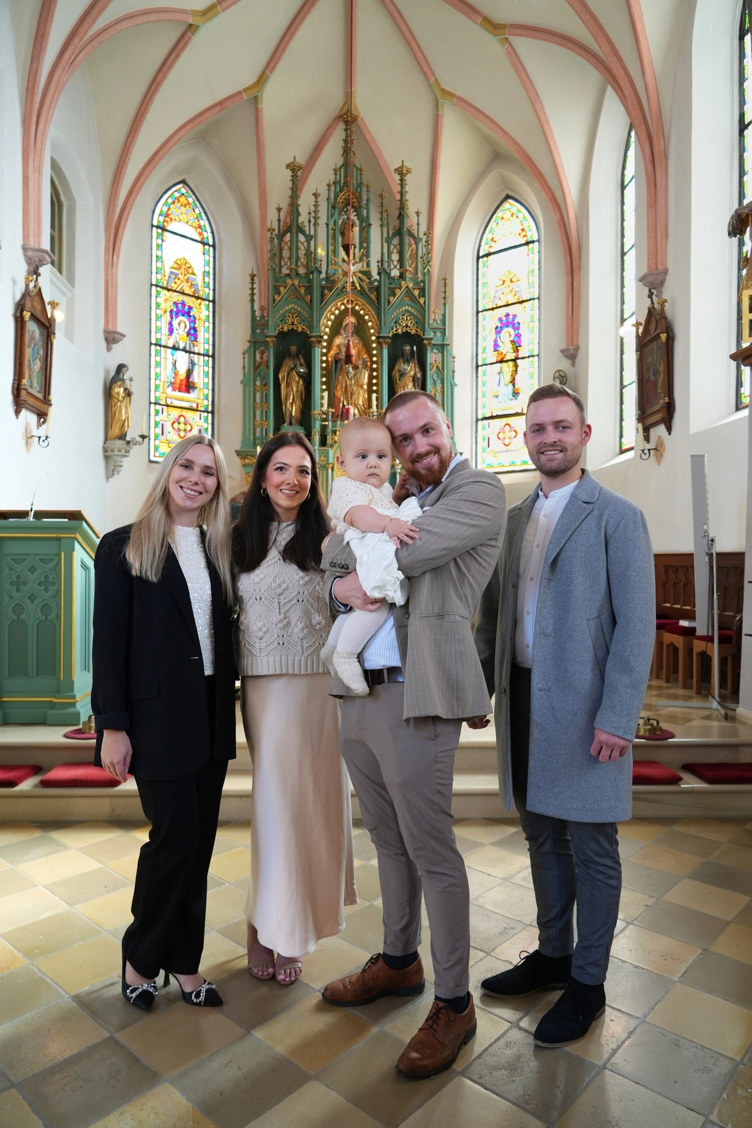 Eine Gruppe Erwachsener steht mit einem Baby gemeinsam in der Kirche.