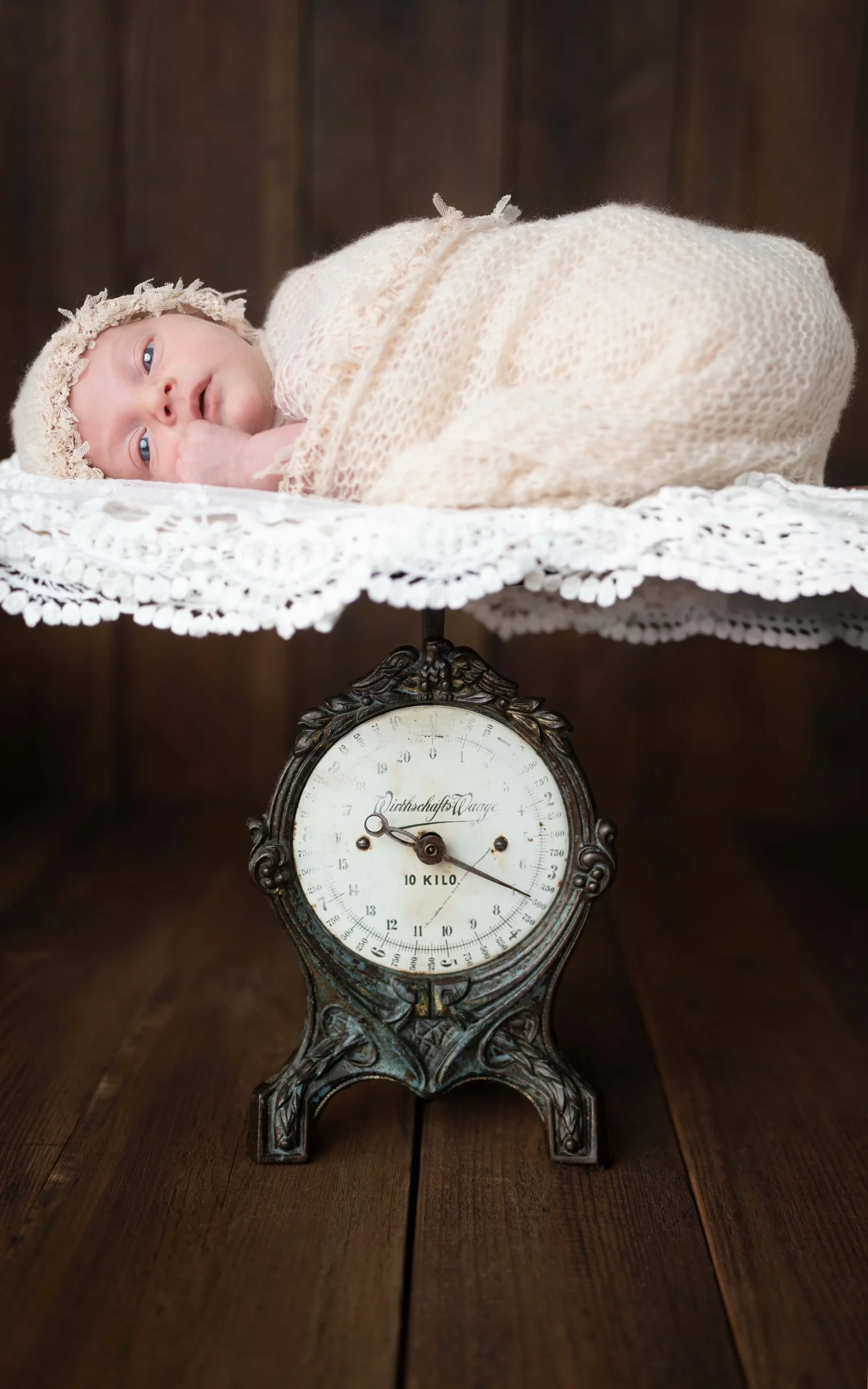 Ein eingewickeltes Baby liegt auf einer weich gepolsterten alten Waage.