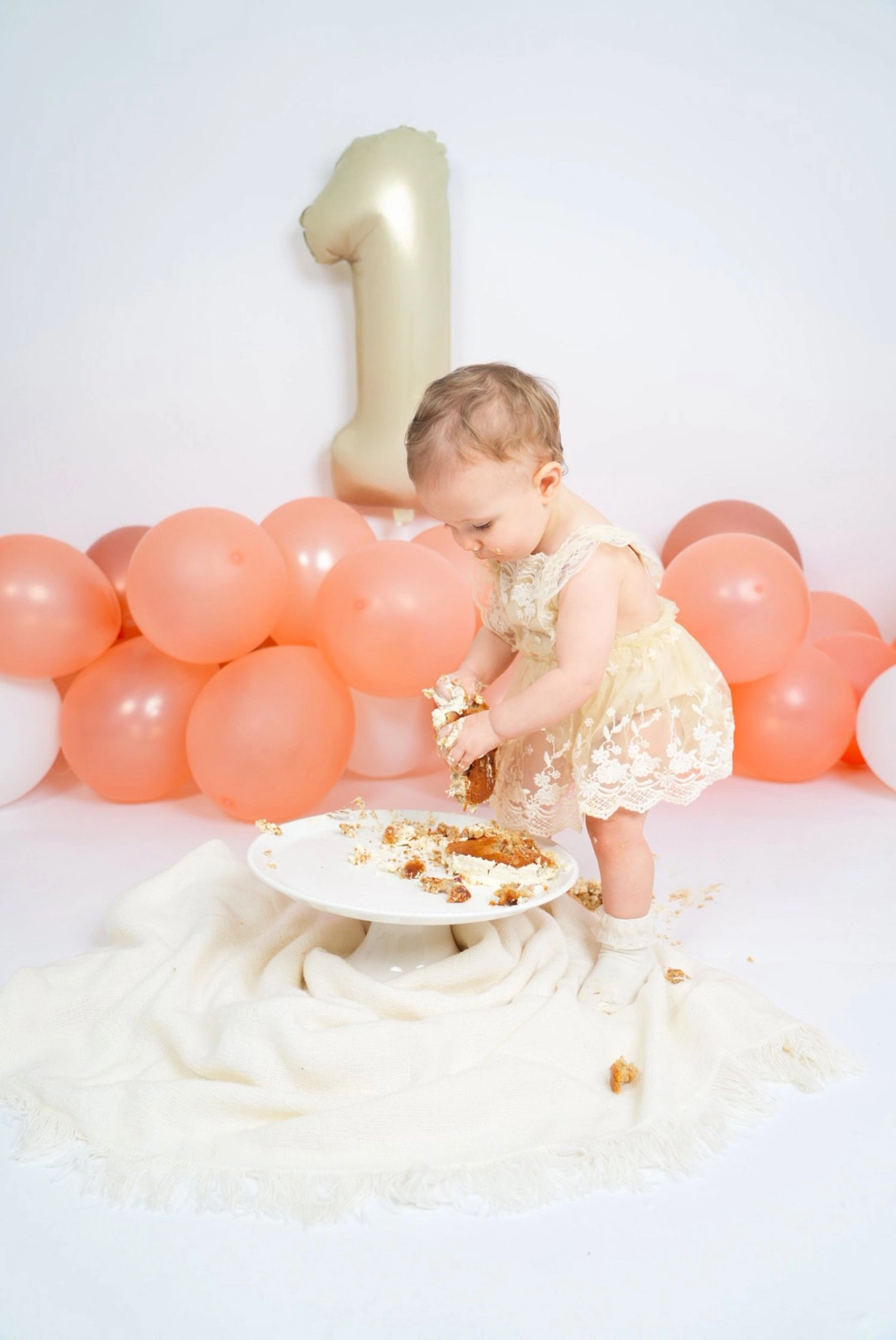 Ein Kind untersucht seine Torte unter einem großen goldenen Einserballon.