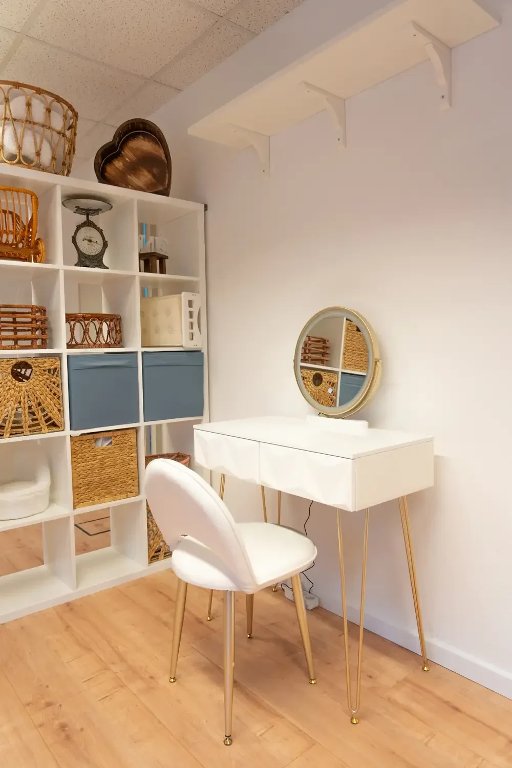 Ein heller Schminkplatz mit rundem Spiegel steht neben einem Studioregal.