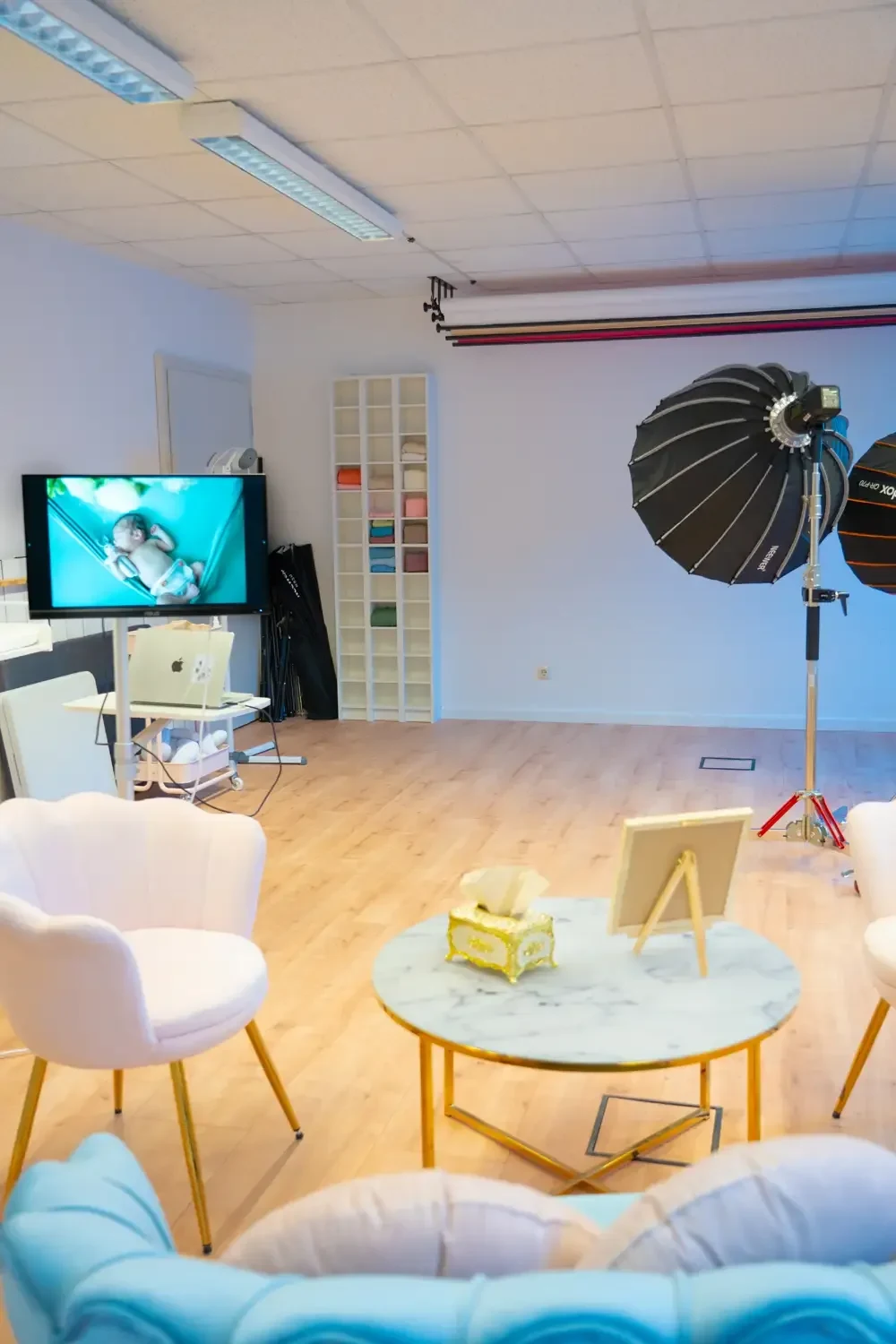 Heller Studioraum mit Sitzecke, kleinem Tisch und aufgebautem Blitzlicht.
