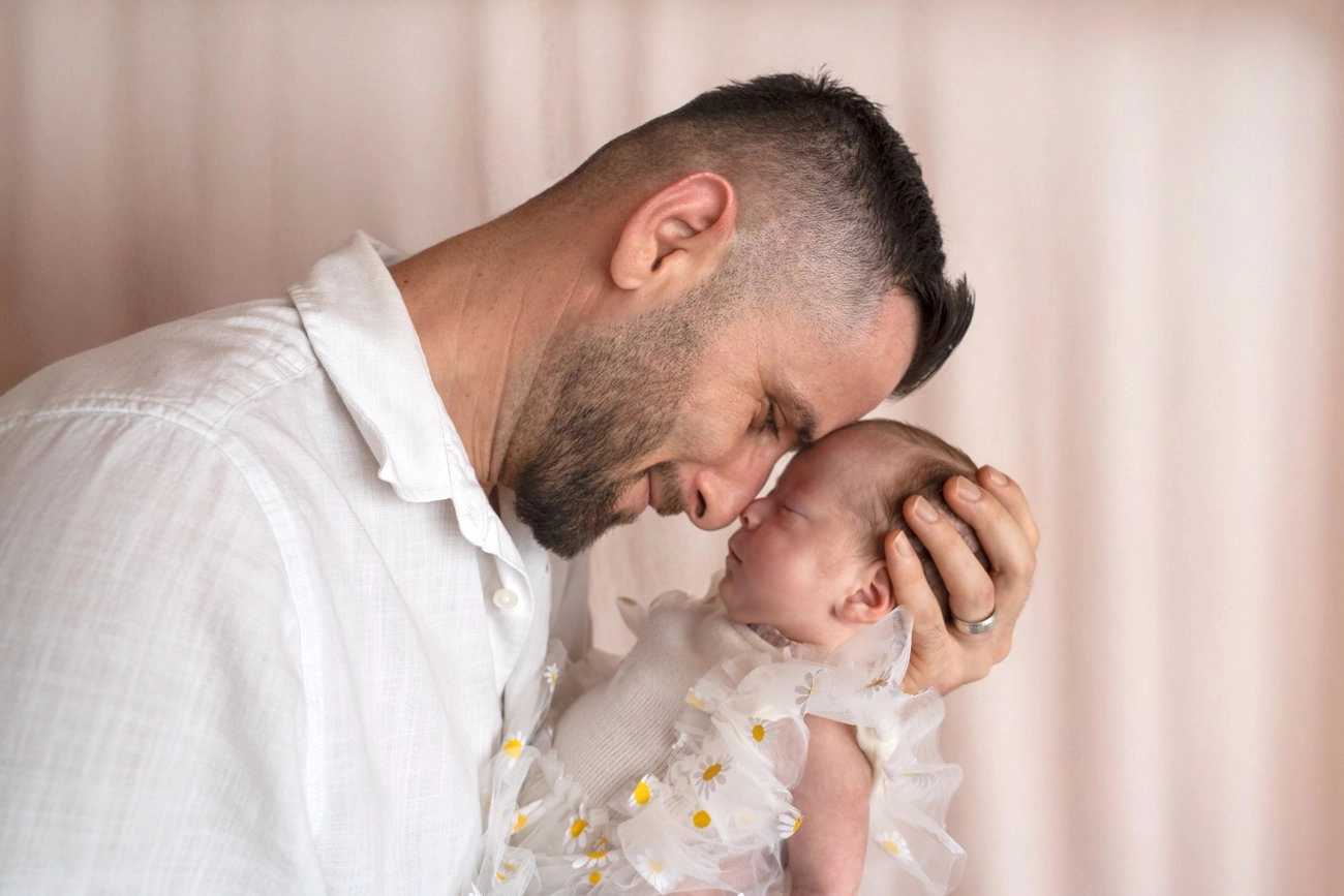 Ein Mann berührt zärtlich die Stirn seines im Arm gehaltenen Babys.
