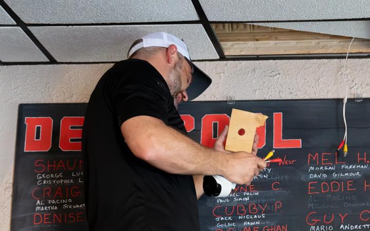 A Reliant technician mounting a device to an interior wall during an installation.