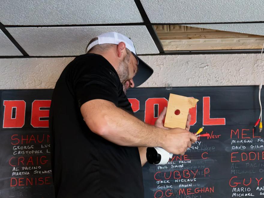 A Reliant technician mounting a device to an interior wall during an installation.