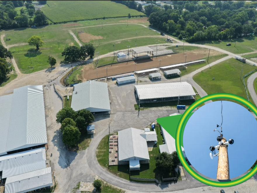 An aerial view of a rural site with a pole-mounted wireless camera picked out in a highlighted circle.