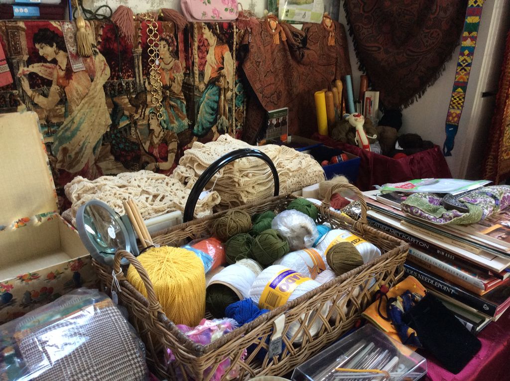 Mand met wol, kant, handwerkpatronen en breiwerk op een tafel