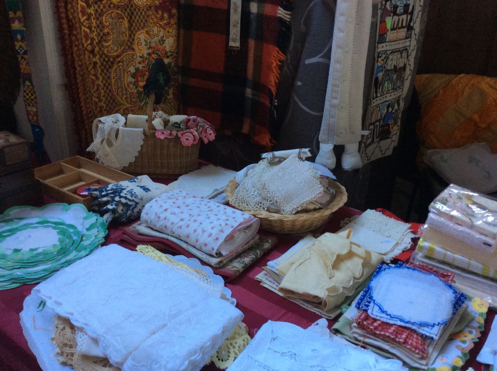 Gestapeld wit en gekleurd handwerk: tafelkleedjes, zakdoeken en kant
