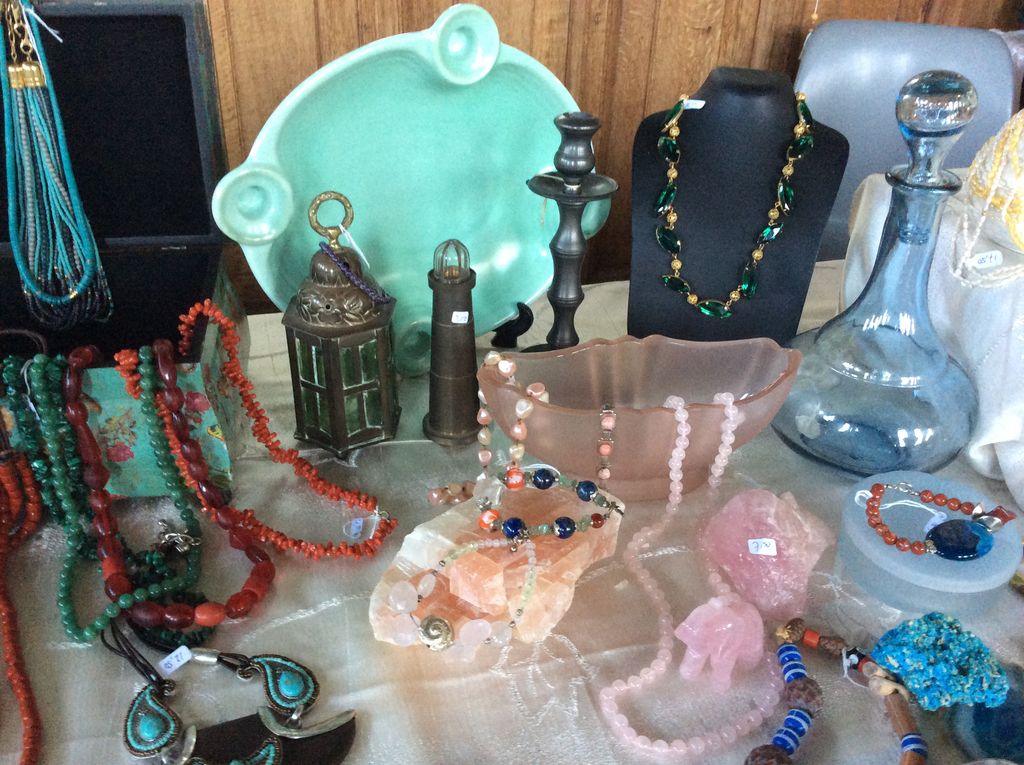 Kettingen van gekleurde stenen, sieraden op een buste en een blauwe karaf
