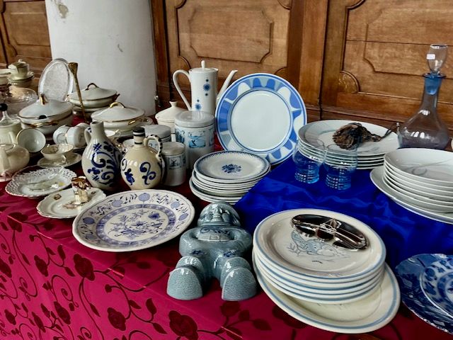 Blauw-wit servies met borden, kannetjes en een karaf op een rood kleed met bloemen