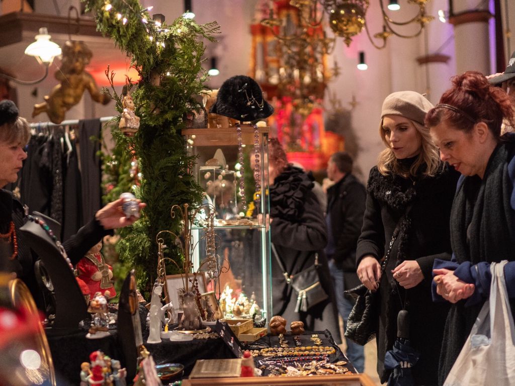 Bezoekers bekijken sieraden en kerstversiering in een kraam met dennentakken