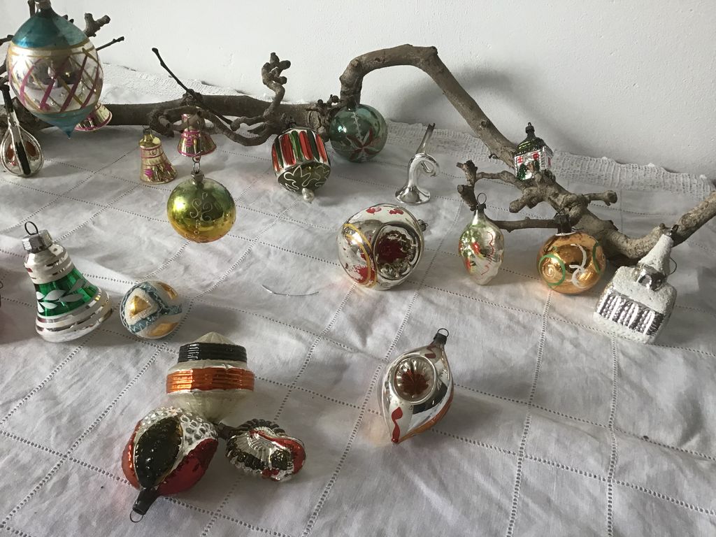 Antieke kerstballen in de vorm van klokjes, huisjes en vruchten op een tak