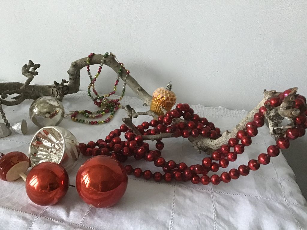 Rode kerstballen, een rode kralenslinger en zilveren ballen op een tak