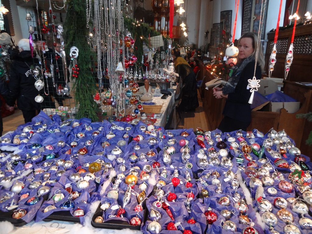 Table full of glass Christmas baubles on blue cloths, with bead garlands above