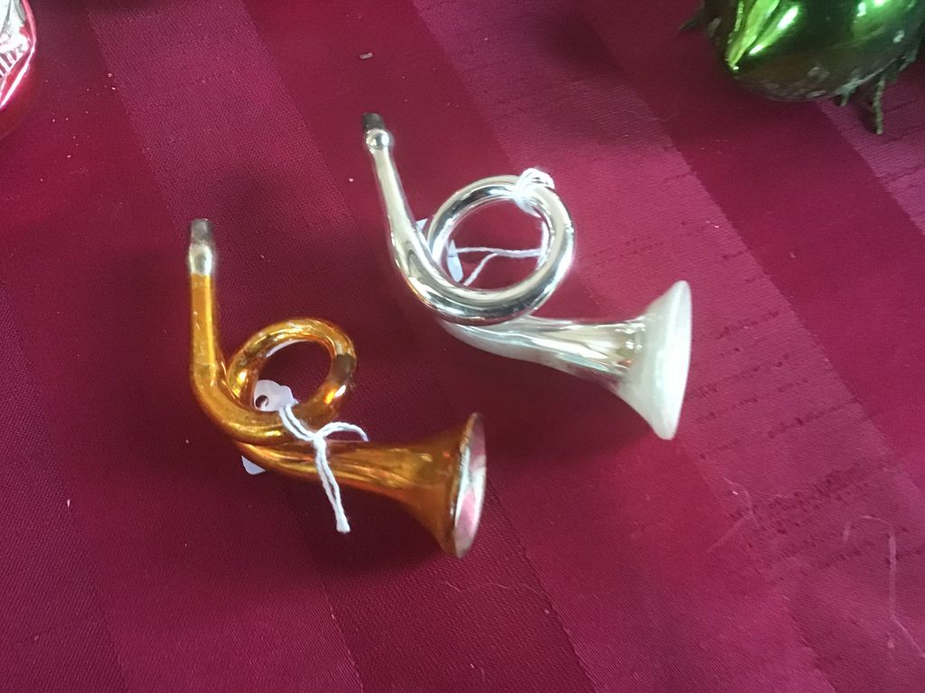 Twee glazen jachthoorns, een gouden en een zilveren, op een rode doek