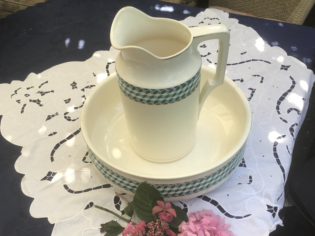White jug and washbasin with a green rim on a white lace cloth