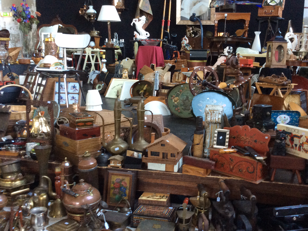 Stall full of copper and wooden items, lamps, small dishes and a small chalet-shaped house