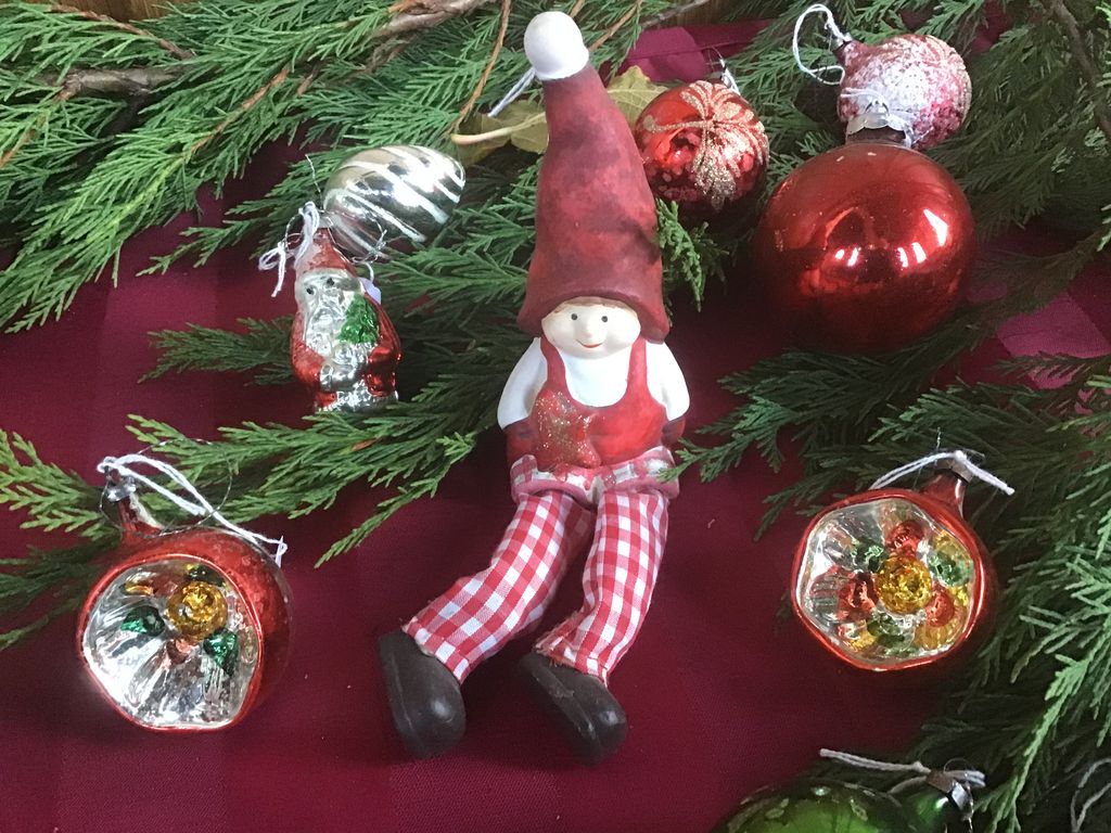 Kerstkabouter met geruite broek tussen rode kerstballen