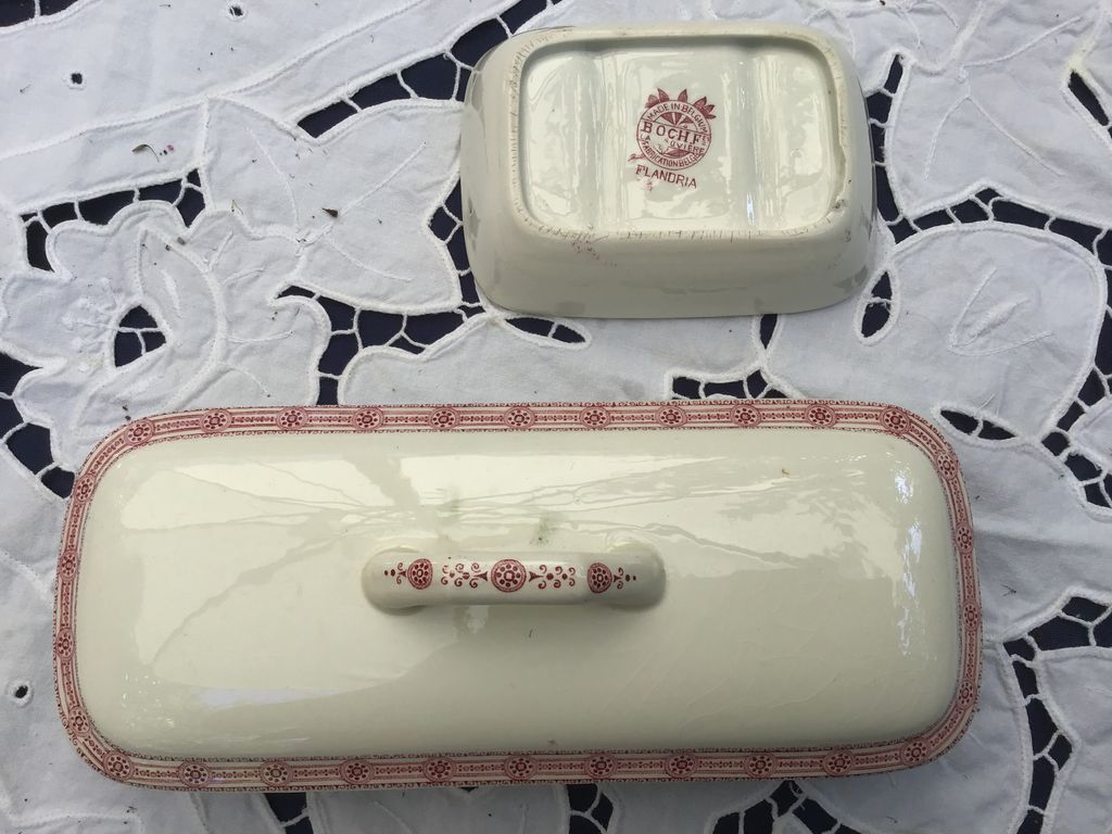 Crèmekleurig zeepbakje met deksel en rood randpatroon op een kanten kleed