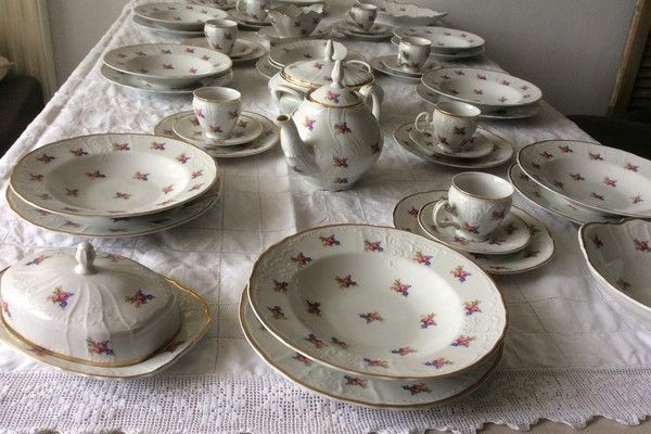 Servies met roosjesmotief: borden, theepot en kopjes op een wit kleed
