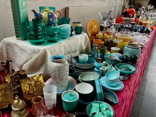Turquoise en groen servies, vazen en koperen plaquettes op een tafel met roze kleed
