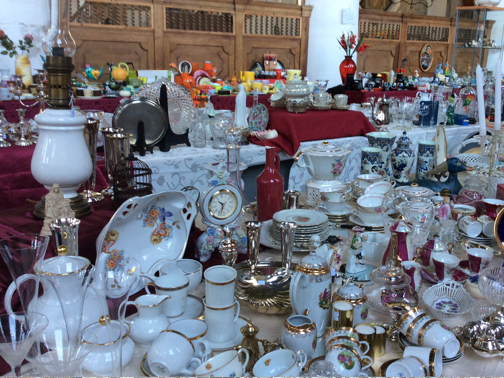 Table full of white porcelain with gold edges, glassware, silver candlesticks, a clock and blue and white vases