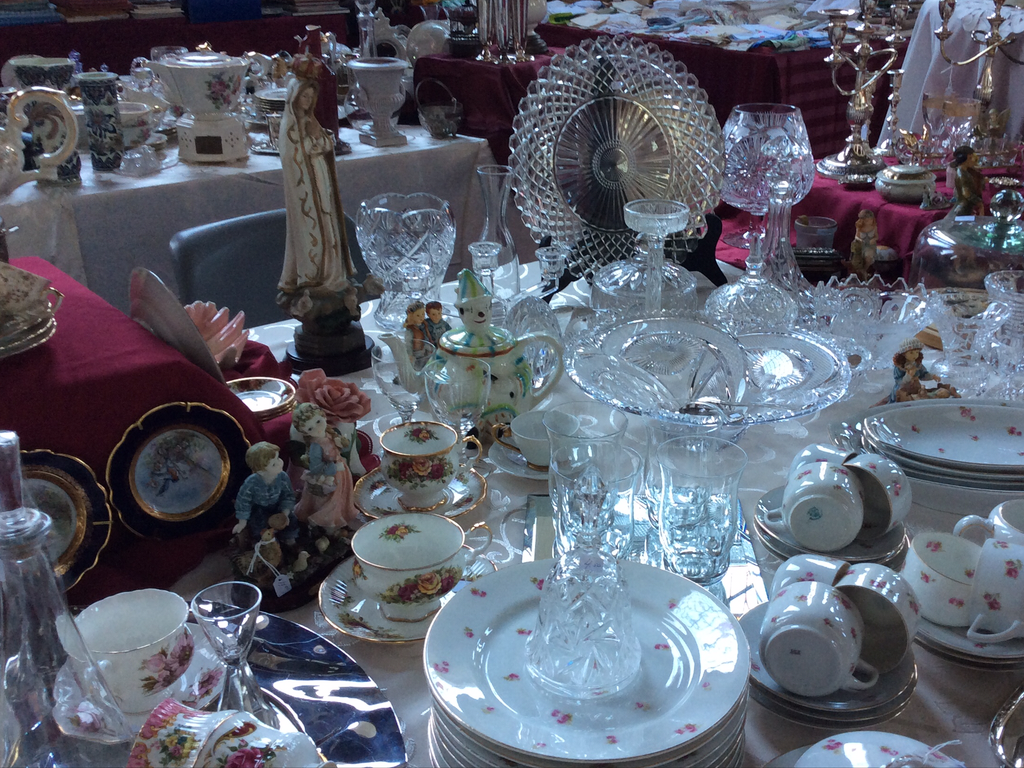 Crystal bowls, glasses and crockery with a rose pattern on a market stall with a burgundy cloth