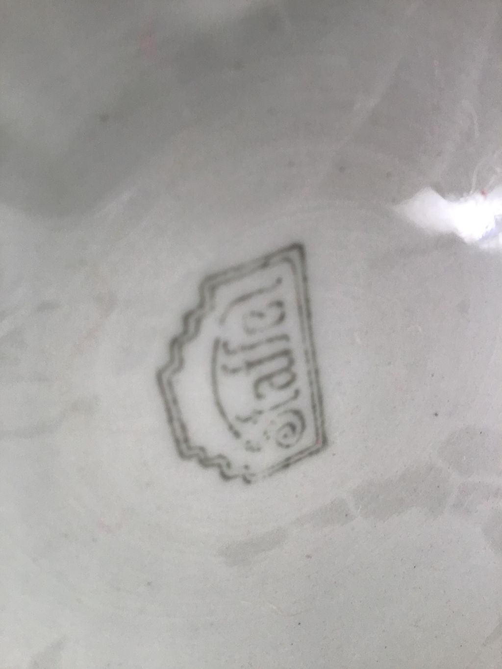Close-up van een merkstempel in zwarte inkt op de onderkant van een wit porseleinen stuk
