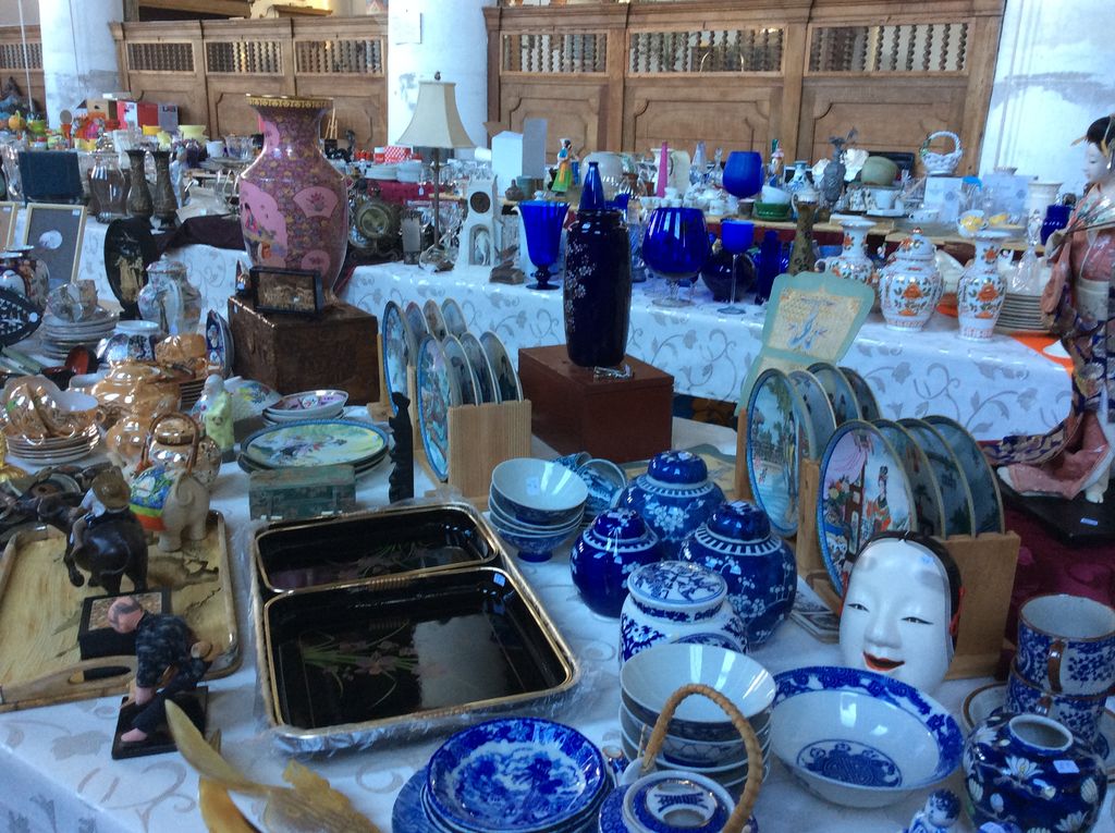 Stall with blue and white porcelain, black lacquer bowls, a pink vase and a Japanese mask