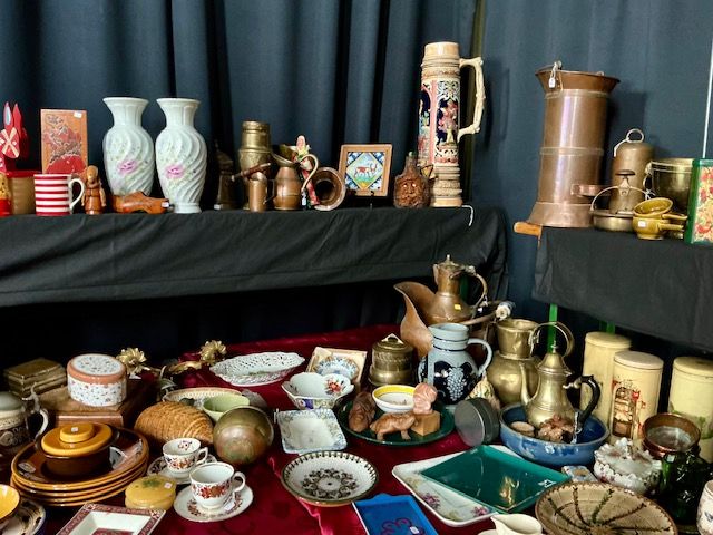 Koperen kannen, vazen en kommen, borden en kopjes op zwarte en rode tafels