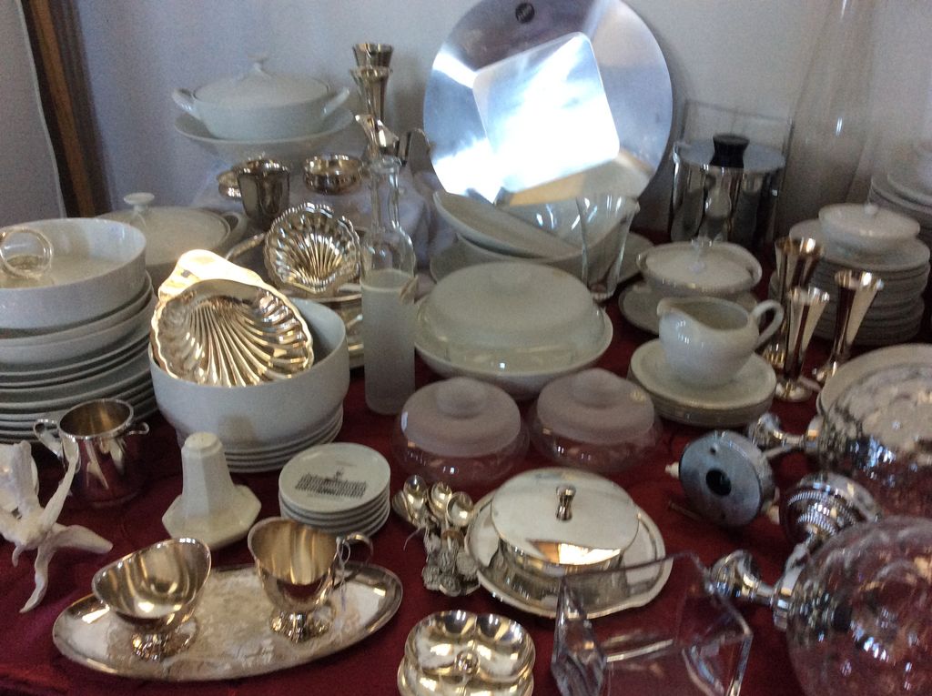 White porcelain and silver-plated tableware with shell dishes, tureens and candlesticks on a red cloth