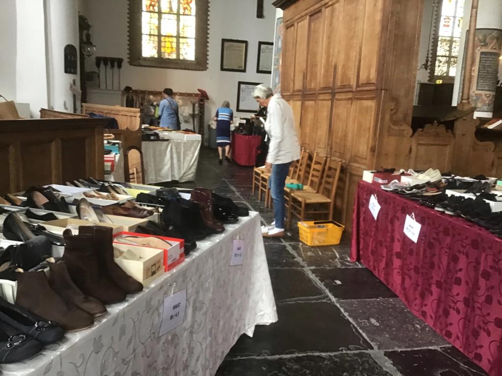 Tafels met schoenen en laarzen in de kerk, bij de houten wand