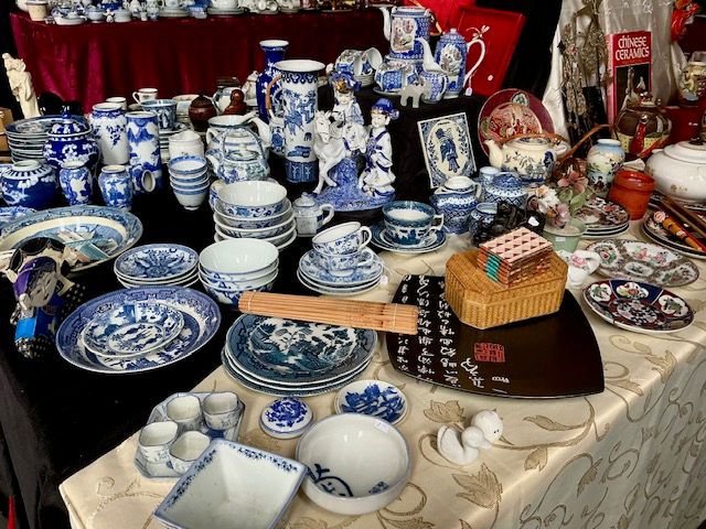 Kraam vol blauw-wit Chinees porselein met borden, kannen, theepotjes en een bamboe mat op een kleed