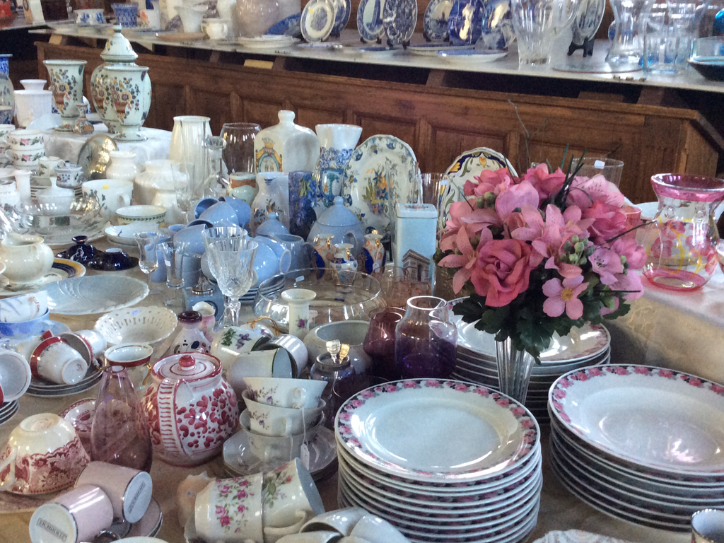Table with porcelain plates, cups and teapots and a bouquet of pink flowers