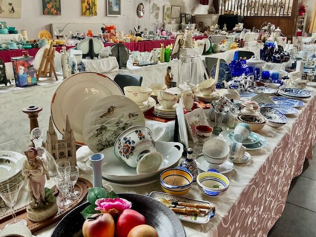 Marktkraam met lange tafel vol borden, schalen, glaswerk en blauw-wit servies en appels in de kerk