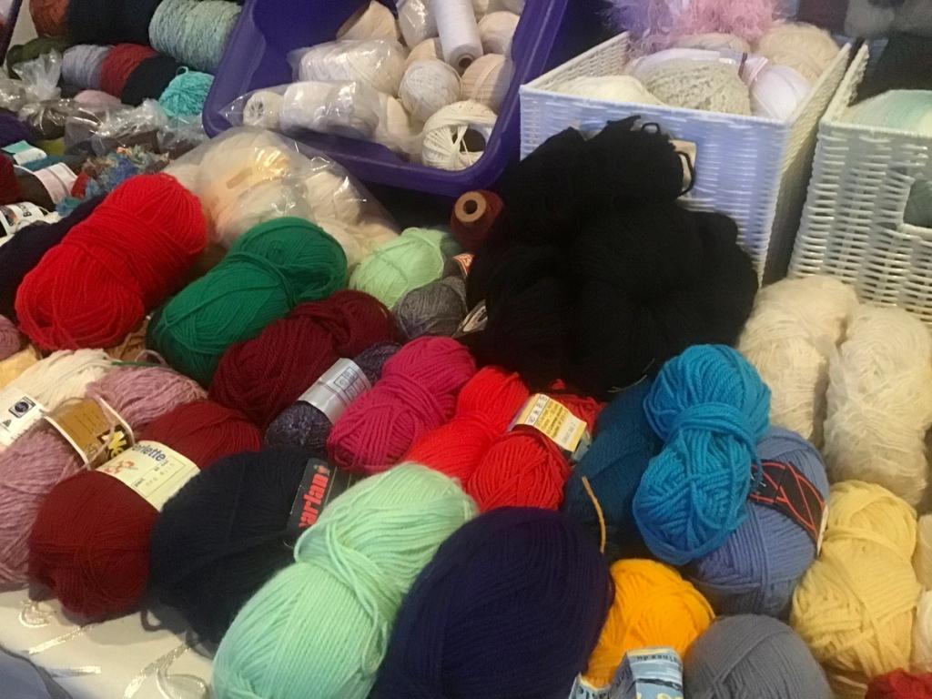 Manden vol wol en garen in rood, groen, blauw en geel
