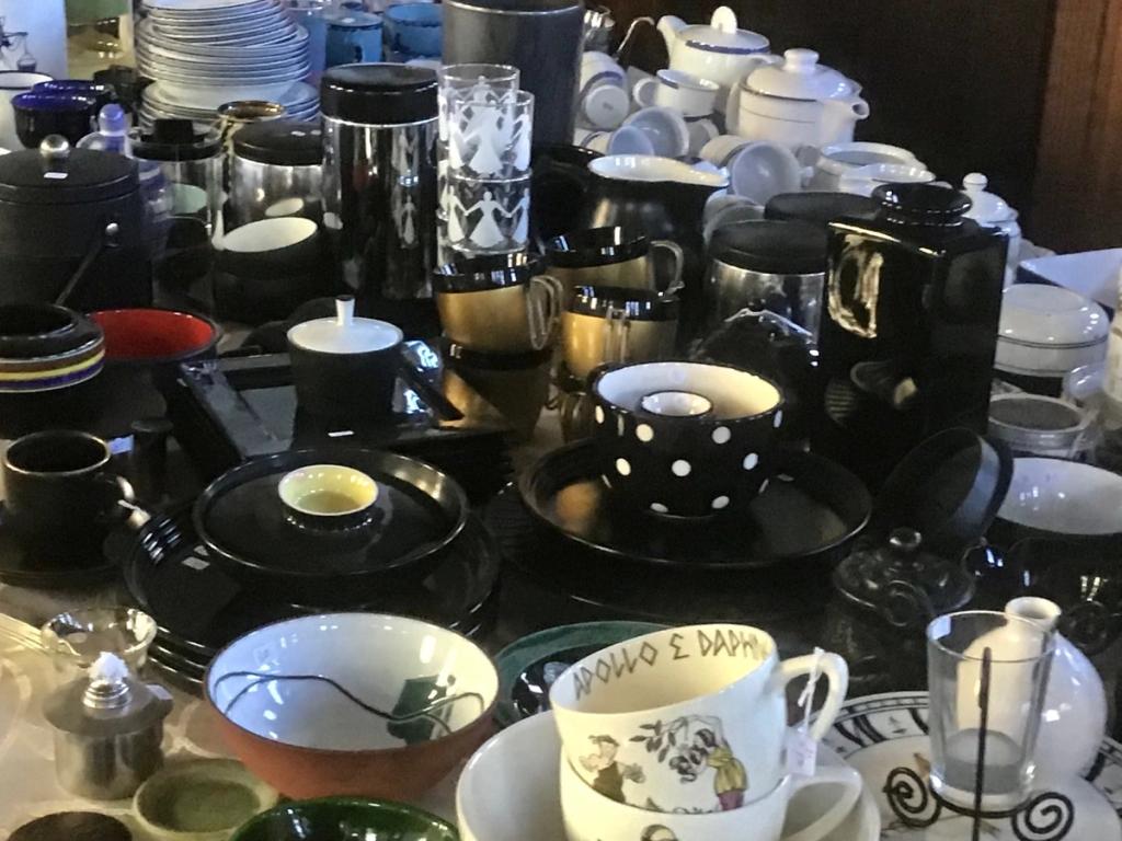 Zwart, goud en wit servies met stippen, kopjes, potten en schalen op een marktkraam