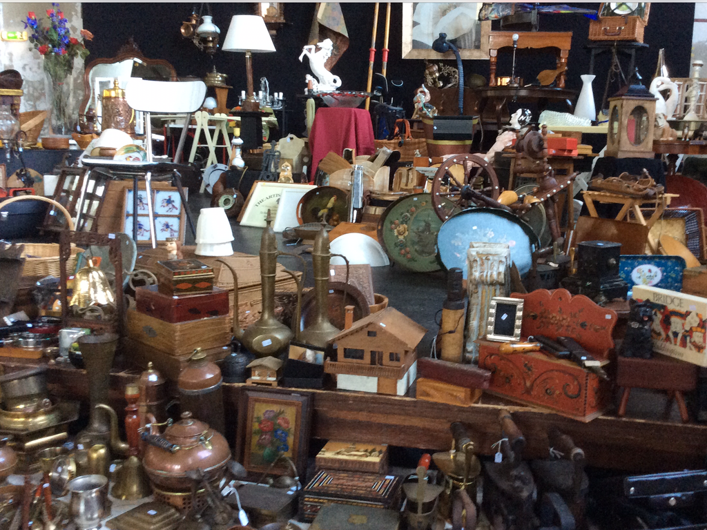 Stalls full of curiosities: copper jugs, wooden boxes, spinning wheel, painted dishes and a birdhouse