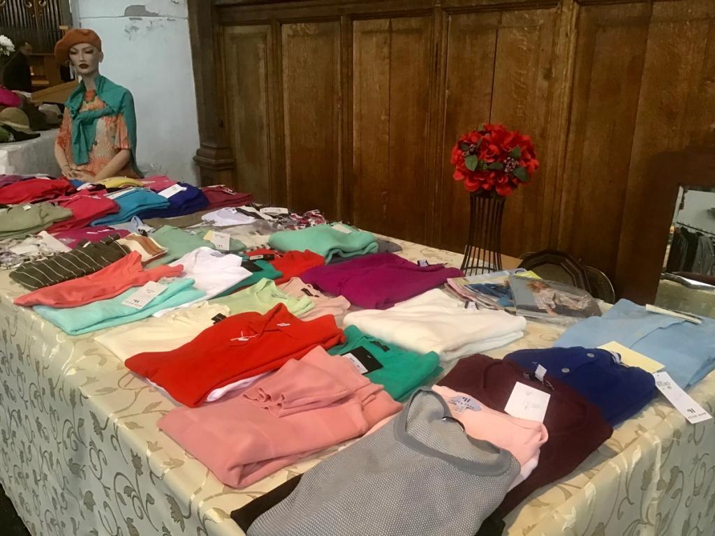 Tafel met gekleurde truien en shirts, met een paspop met sjaal