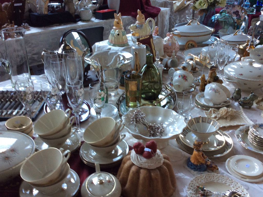 Table with cups, soup tureens, crystal glasses, a dish with teaspoons and a cake with raspberries