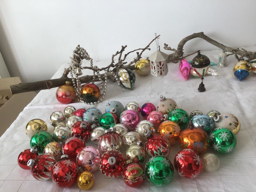 Veelkleurige glazen kerstballen met sterretjes op een wit kleed