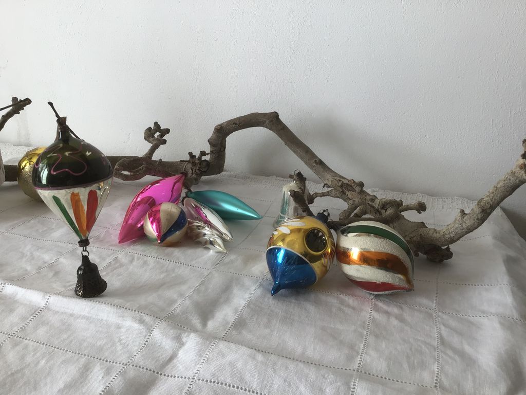 Kleurige glazen kerstballen en een belletje op een tak