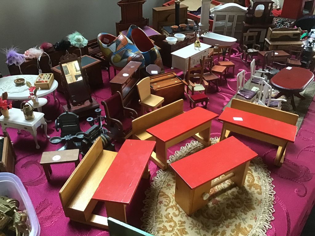 Wooden doll's house furniture, including red tables and benches, on a small cloth