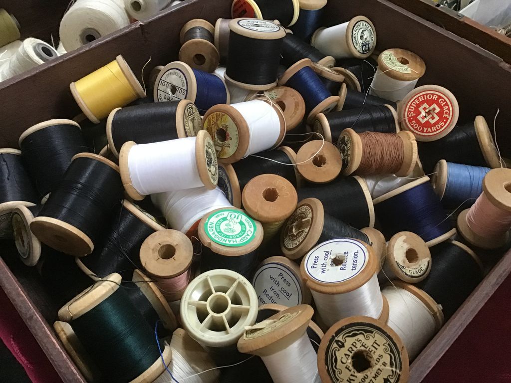 Doos met oude houten garenklosjes in verschillende kleuren