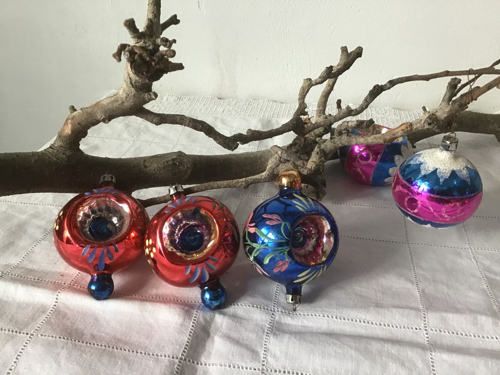 Rode en blauwe antieke kerstballen met een inham, naast een tak
