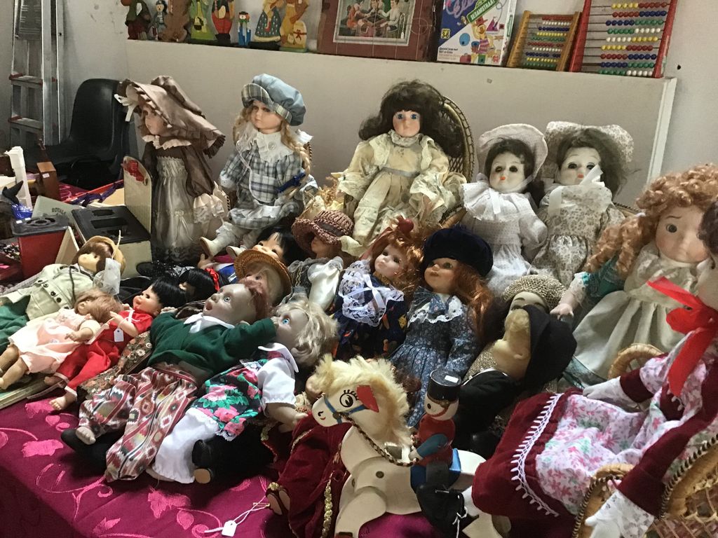 Collection of porcelain dolls and a small wooden horse on a red cloth