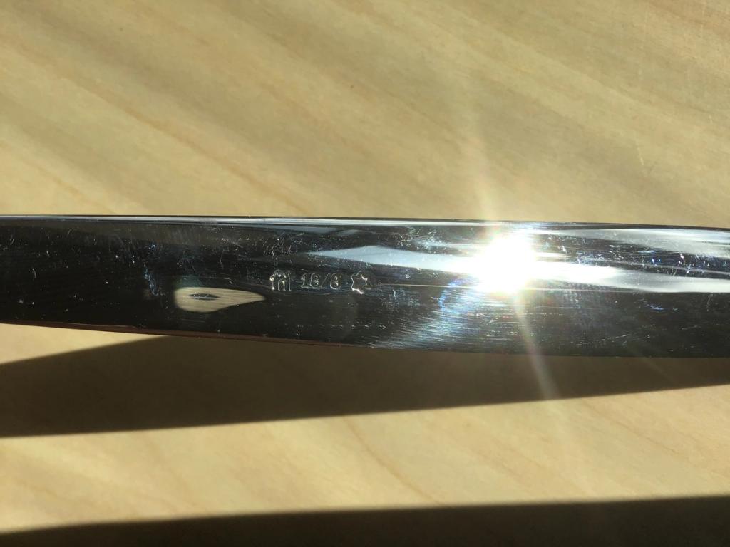 Close-up of a shiny piece of cutlery with the stamp 18/8 on a wooden surface