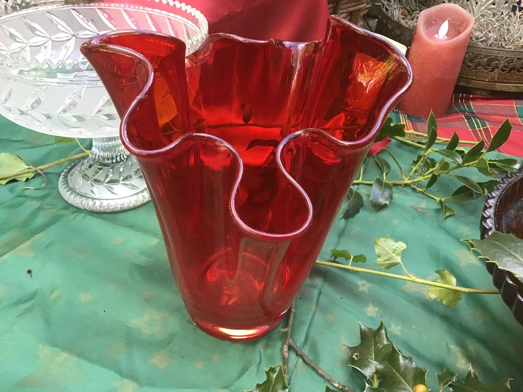 Red glass vase with a wavy rim on a green cloth
