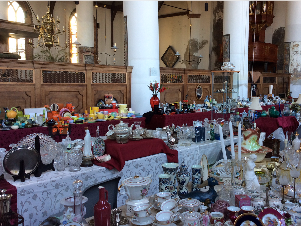 Market stalls full of crockery, candlesticks and glassware on red and white cloths in the church